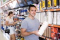 Skilled young handyman choosing painter tape in hardware store Royalty Free Stock Photo