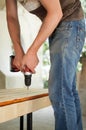 Skilled young male worker is using power screwdriver drilling during construction wooden bench, do it yourself Royalty Free Stock Photo