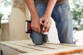 Skilled young male worker is using power screwdriver drilling during construction wooden bench, do it yourself Royalty Free Stock Photo