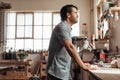 Skilled young woodworker leaning on a workbench deep in thought