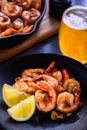 Skillet roasted jumbo shrimp with sliced garlic and spices on a black plate