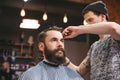 Skillful barber cutting hair of young man with beard Royalty Free Stock Photo