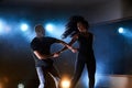 Skillful dancers performing in the dark room under the concert light and smoke. Sensual couple performing an artistic