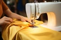 Skillful female hands work on a modern sewing machine, stitching yellow fabric
