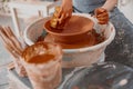 Skillful female potter creating earthen bowl on circle in workroom