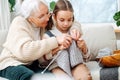 Skillful granny tutoring her granddaughter, teaching her how to knit Royalty Free Stock Photo