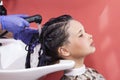 Skillful hairdresser washes hair before styling, long haired teen girl in hair salon