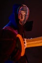 Close up shot, Kendo fighter wearing in an armor, traditional kimono, helmet practicing martial art with shinai bamboo