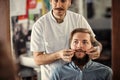 Skillful male barber is serving his client