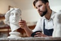 Skillful sculptor makes professional restauration of gypsum sculpture of woman`s head at the creative workshop.