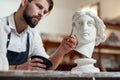 Skillful sculptor makes professional restauration of gypsum sculpture of woman`s head at the creative workshop. Royalty Free Stock Photo