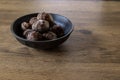 Skin-on boiled taro corm in a black crockery on a wooden table.