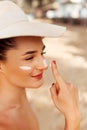 Skin care. Beauty Concept. Young pretty woman applying sun cream  and touch own face. Royalty Free Stock Photo