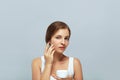 Skin care. Beauty Concept. Young pretty woman holding  cosmetic cream and applying on her face. Royalty Free Stock Photo