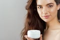 Skin care. Beauty Concept. Young pretty woman holding cosmetic cream. Soft skin and naked shoulders Royalty Free Stock Photo