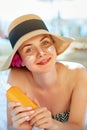 Skin care. Beauty Concept. Young pretty woman holding  sun cream and applying on her face. Female in hat smear  sunscreen lotion Royalty Free Stock Photo