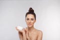 Skin care. Beauty Concept. Young woman holding cosmetic moisturizing cream. Soft skin and naked shoulders, model with light nude m Royalty Free Stock Photo