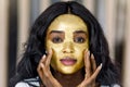 Skin care, beauty, spa. Pretty African woman with golden face mask. Close up of beautiful sexy girl with cosmetic Royalty Free Stock Photo