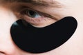 Skin care. Black pearl extract. Minimizes puffiness and reduce dark circles. Eye patches for men. Man with black eye Royalty Free Stock Photo