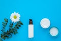 Skin care concept. Cream and lotion in glass bottle, cosmetic product, moisturizer with chamomile, face cream on blue background. Royalty Free Stock Photo