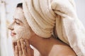 Skin Care concept. Young happy woman in towel making facial massage with organic face scrub close up in stylish bathroom. Girl Royalty Free Stock Photo