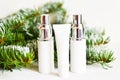 Skin care cosmetics bottles on a fir branches background. Blank containers on a wooden white background. Christmas present for wom