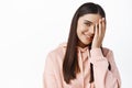 Skin care. Portrait of smiling brunette woman covering half of face and looking happy, wearing natural light make up Royalty Free Stock Photo