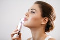 Skin Care. Side portrait of the charming healthy fresh woman with natural make-up using the electric facial massager at