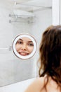 Skin care. Woman touching hair and smiling while looking in the mirror.Portrait of happy girl with wet hair in bathroom Royalty Free Stock Photo