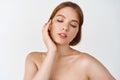 Skin care and women beauty. Gentle young woman naked shoulders, touching natural facial skin without makeup, apply daily