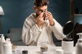 Skin cleaning. Handsome bearded man applying black textile mask on nose. Soft male facial skin using black nose patch