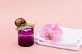 Skin rejuvenation cosmetics on pink background with snail, flower and white towel, snail mucin cream, skin hydration, beauty, spa