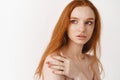 Skincare and beauty concept. Close-up of tender young redhead woman with pale skin, natural ginger hair, touching Royalty Free Stock Photo