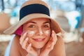 Skincare. Beauty Concept. Young pretty woman applying sun cream  and touch own face. Female in hat smear  sunscreen lotion on skin Royalty Free Stock Photo