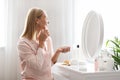 Skincare Concept. Attractive Middle Aged Lady Applying Moisturising Face Cream At Home Royalty Free Stock Photo