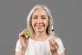 Daily skincare. Feminine mature woman advertising organic cosmetics, showing facial serum with fruit acids and lime