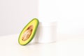 Skincare with natural cosmetics. White cosmetic jar of cream with half of the avocado near against white background