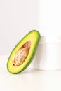 Skincare with natural cosmetics. White cosmetic jar of cream with half of the avocado near against white background