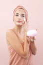 Skincare, pretty young woman applying moisturizing cream on face, lotion or mask for skin lifting and anti-aging, wears wrapped Royalty Free Stock Photo