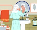 Skincare routine. Everyday beauty procedure. Woman washing face and applying cosmetic cream. Girl in bathrobe standing