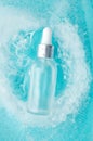 Skincare serum essence glass bottle with water drops in ice blue background, vertical. Concept summertime beauty product, top view