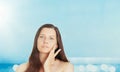 Skincare and sun protection in summer. Portrait of a beautiful young suntanned woman, blue sea and sky on background