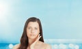 Skincare and sun protection in summer. Portrait of a beautiful young suntanned woman, blue sea and sky on background