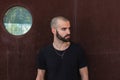 Skinhead man standing against rustic wall