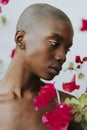 Skinhead woman surrounded by red flowers