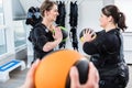 Skinny and big woman having ems training with medicine ball