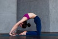 Skinny flexible female yogini bending backwards doing stretching exercises on floor in a room Royalty Free Stock Photo