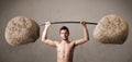 Skinny guy lifting large rock stone weights Royalty Free Stock Photo