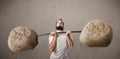 Skinny guy lifting large rock stone weights Royalty Free Stock Photo