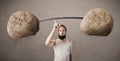 Skinny guy lifting large rock stone weights Royalty Free Stock Photo